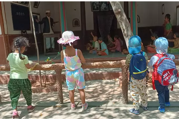 Children looking at a real life size model of old school or Gurukul way of learning in Model Village, Bengaluru during a field trip organized for children by Olivia Montessori